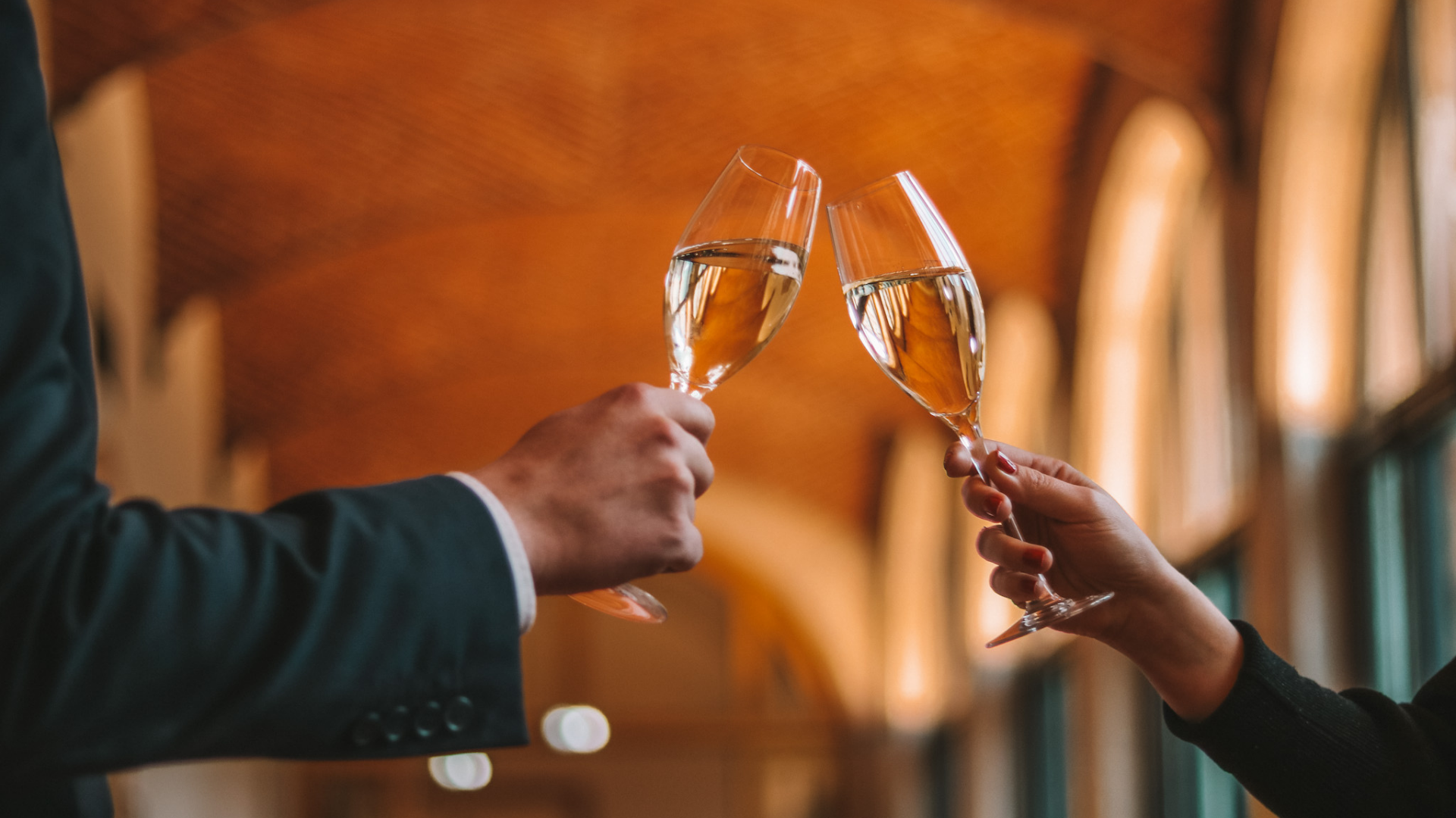 Deux personnes trinquent avec des flûtes de champagne.
