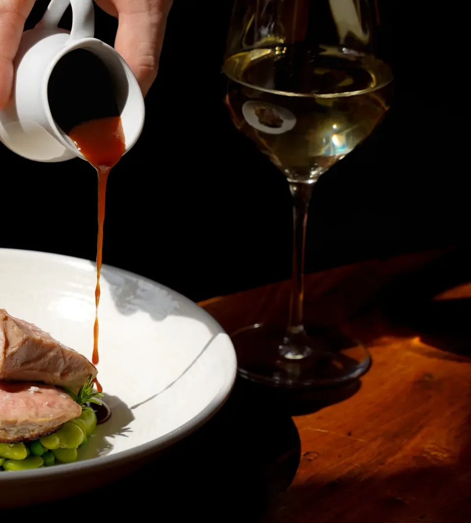 Plat gastronomique avec sauce versée, verre de vin.